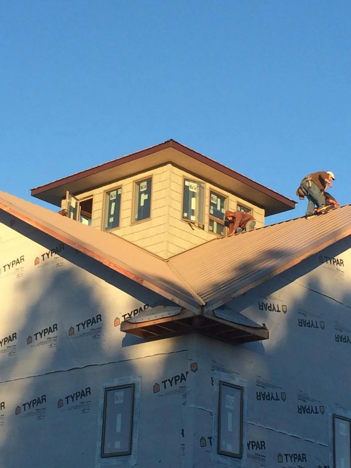 Roofers working around a rooftop cupola on a new metal roof at sunset — Roof Waterproofing in Waldo by Roofing Brothers